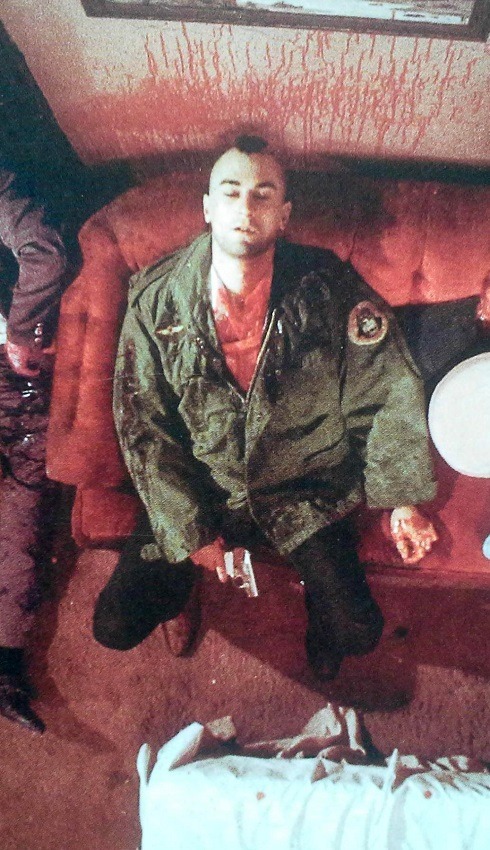 Travis Bickle, blutbedeckt mit einer Pistole in der Hand auf einem Sofa sitzend