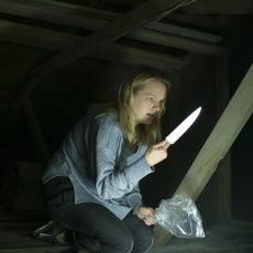 Cecilia aus "Der Unsichtbare" mit einem Messer bewaffnet auf dem Dachboden