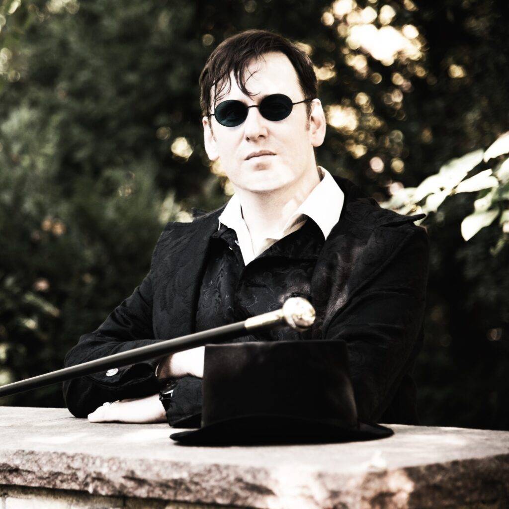 Marius Tahira mit Sonnenbrille und Spazierstock im Gehrock.
