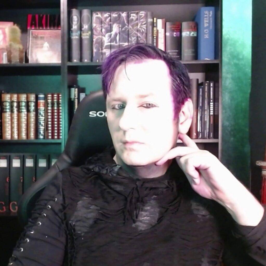 Marius Tahira, rank und schlank posierend, im Gothic-Outfit mit lila Haaren